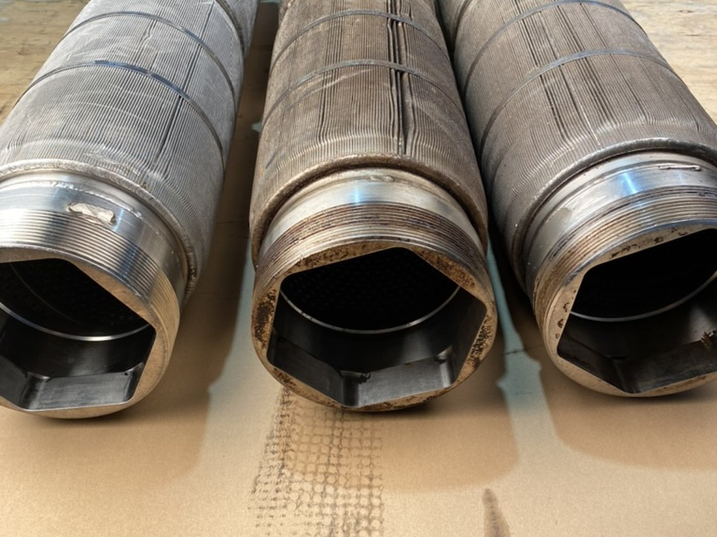 Three pleated mesh filter elements mid-job: the one on the left already cleaned, the two beside it still fouled