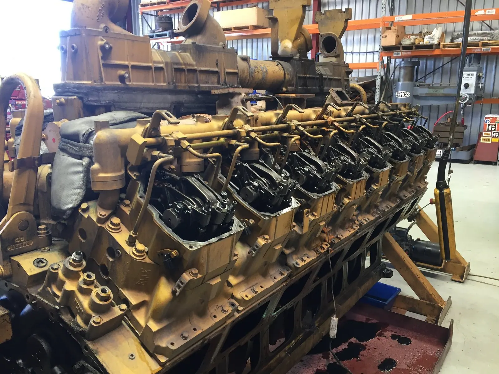 Caterpillar 3516 engine stripped on a stand with sixteen individual cylinder heads along the bank
