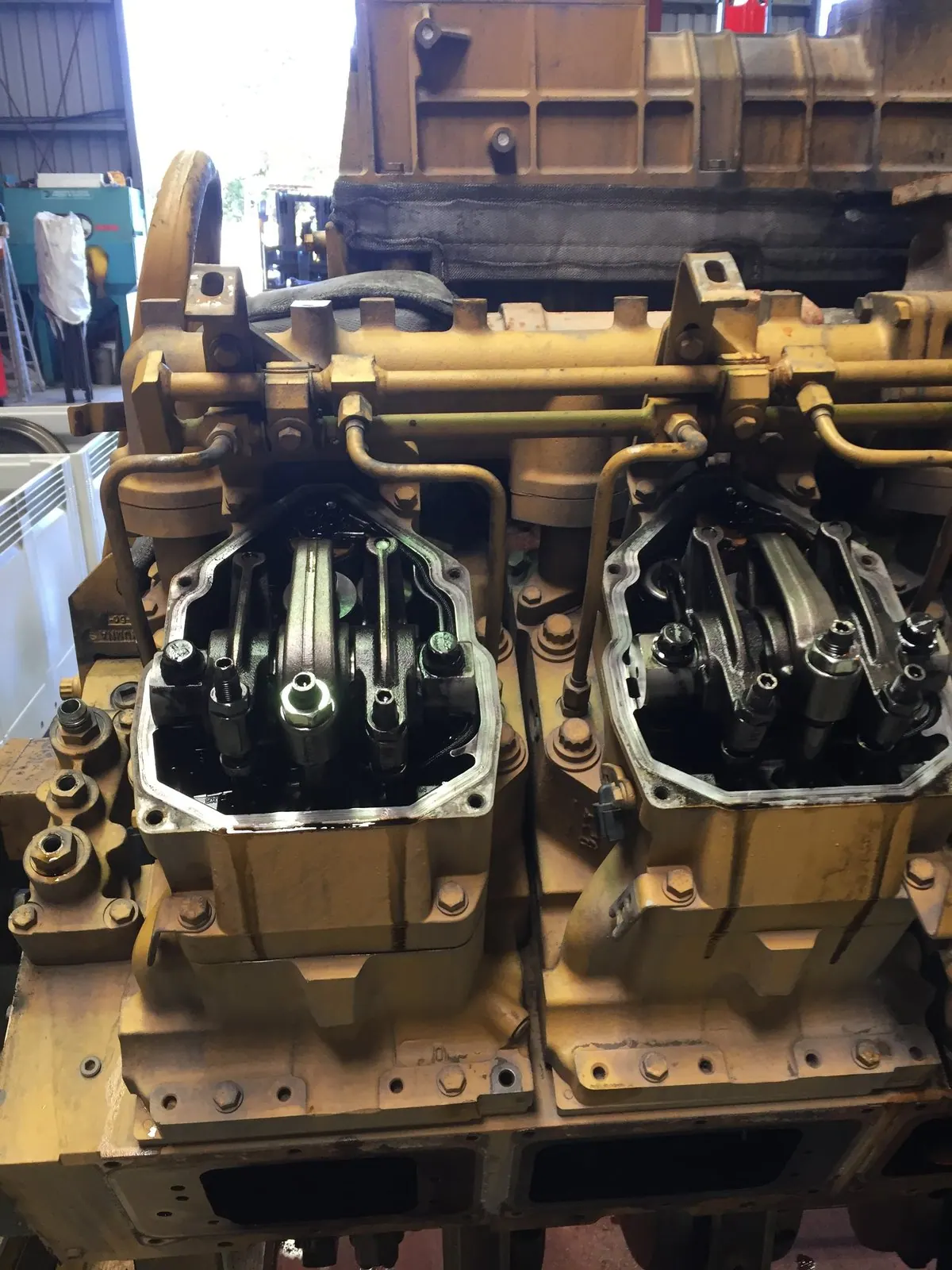 Two adjacent Cat 3516 cylinder heads, four studs each, valve gear exposed