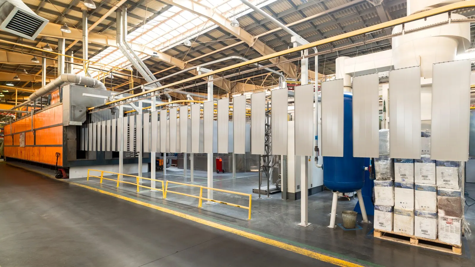 Powder coating line — panels on an overhead conveyor entering the curing oven