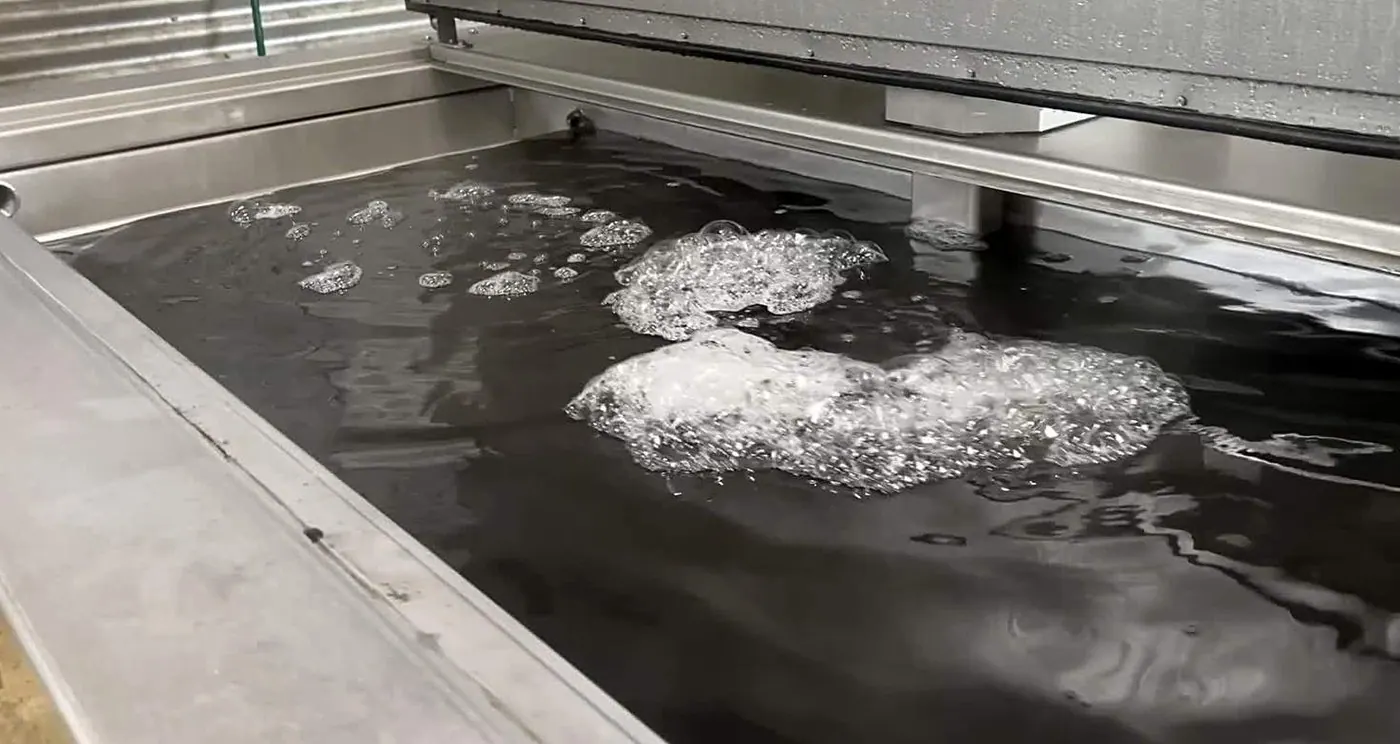Cavitation clouds breaking at the surface of a working ultrasonic bath