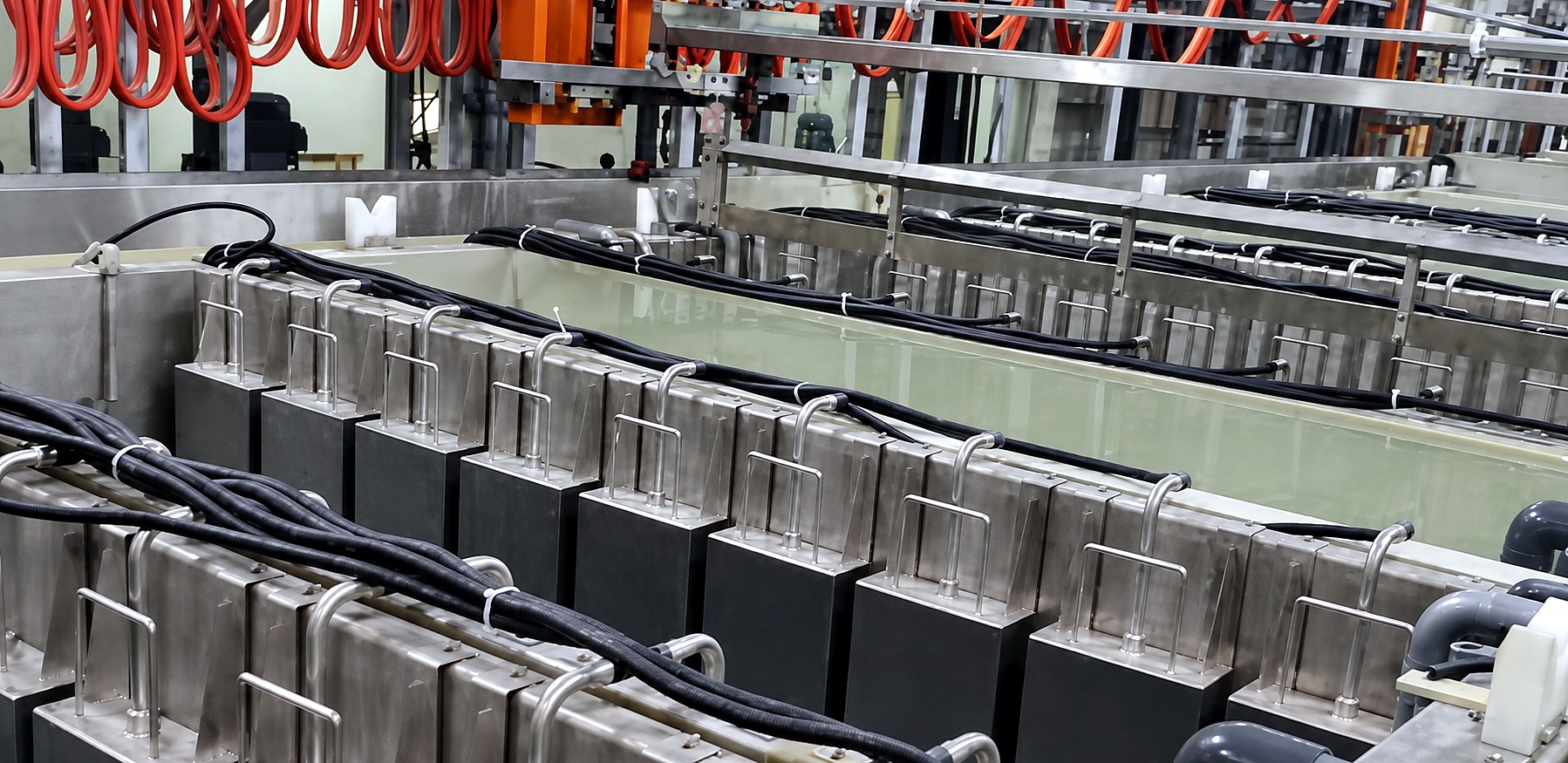 A row of immersible transducer boxes hung on the rims of plating tanks, each with its cable dressed back along the line