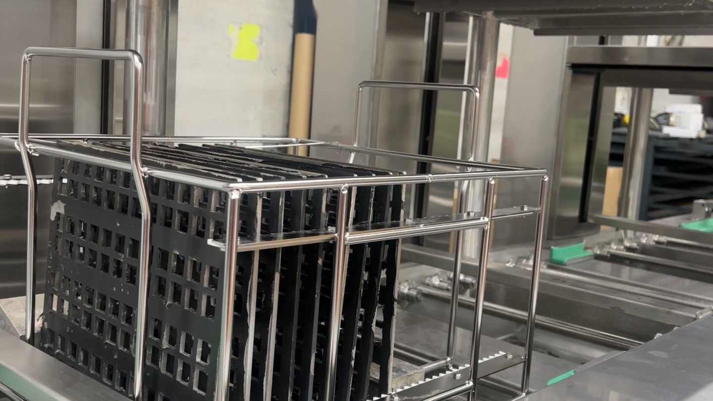 A rack of parts held above the ultrasonic wash tank of a Misonics Sono L-130 line