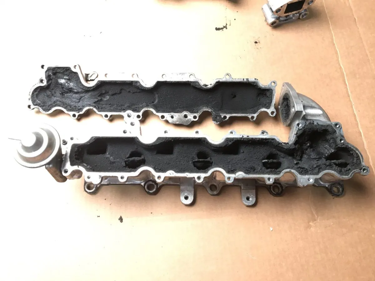 Aluminium inlet manifolds as they arrived, black with baked oil and carbon.
