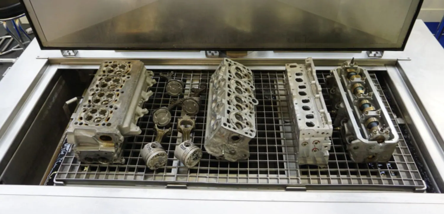 Cylinder heads, pistons and rods on the tray of an UltraTecno ACM ultrasonic cleaner